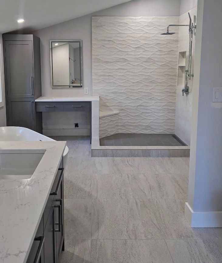 Modern bathroom with a walk-in shower, textured tiles, and gray cabinetry.