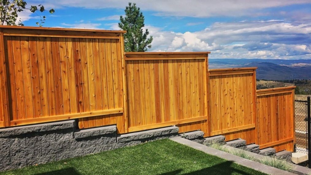 Tall cedar fence going down a stepped hillside.