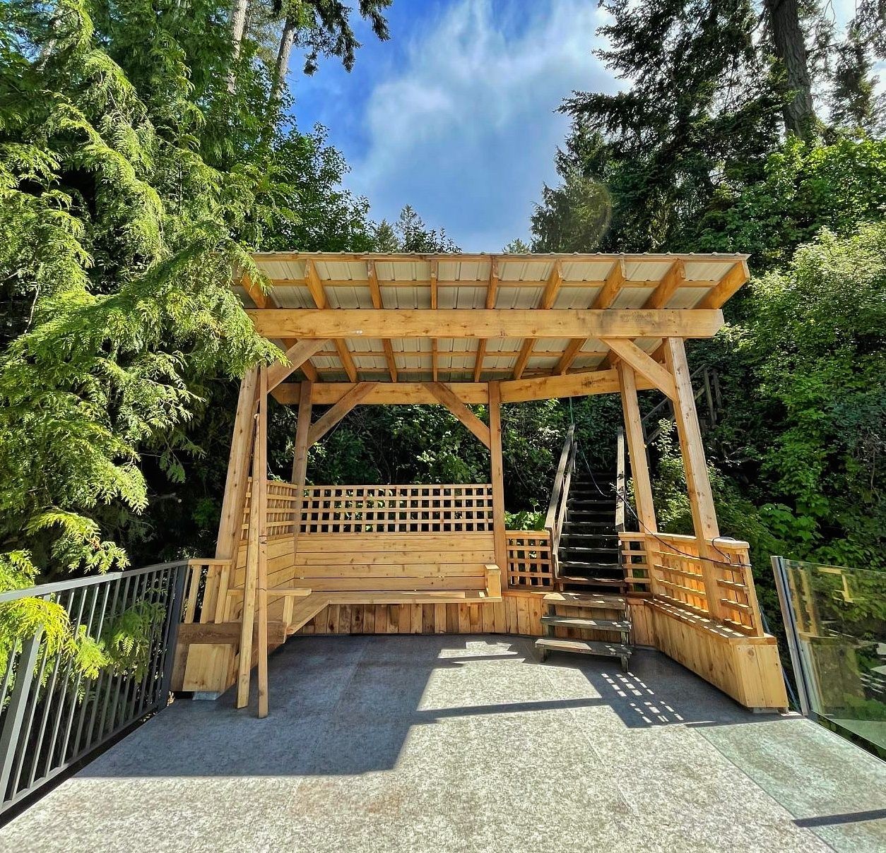 Wooden pergola surrounded by shrubs and trees.